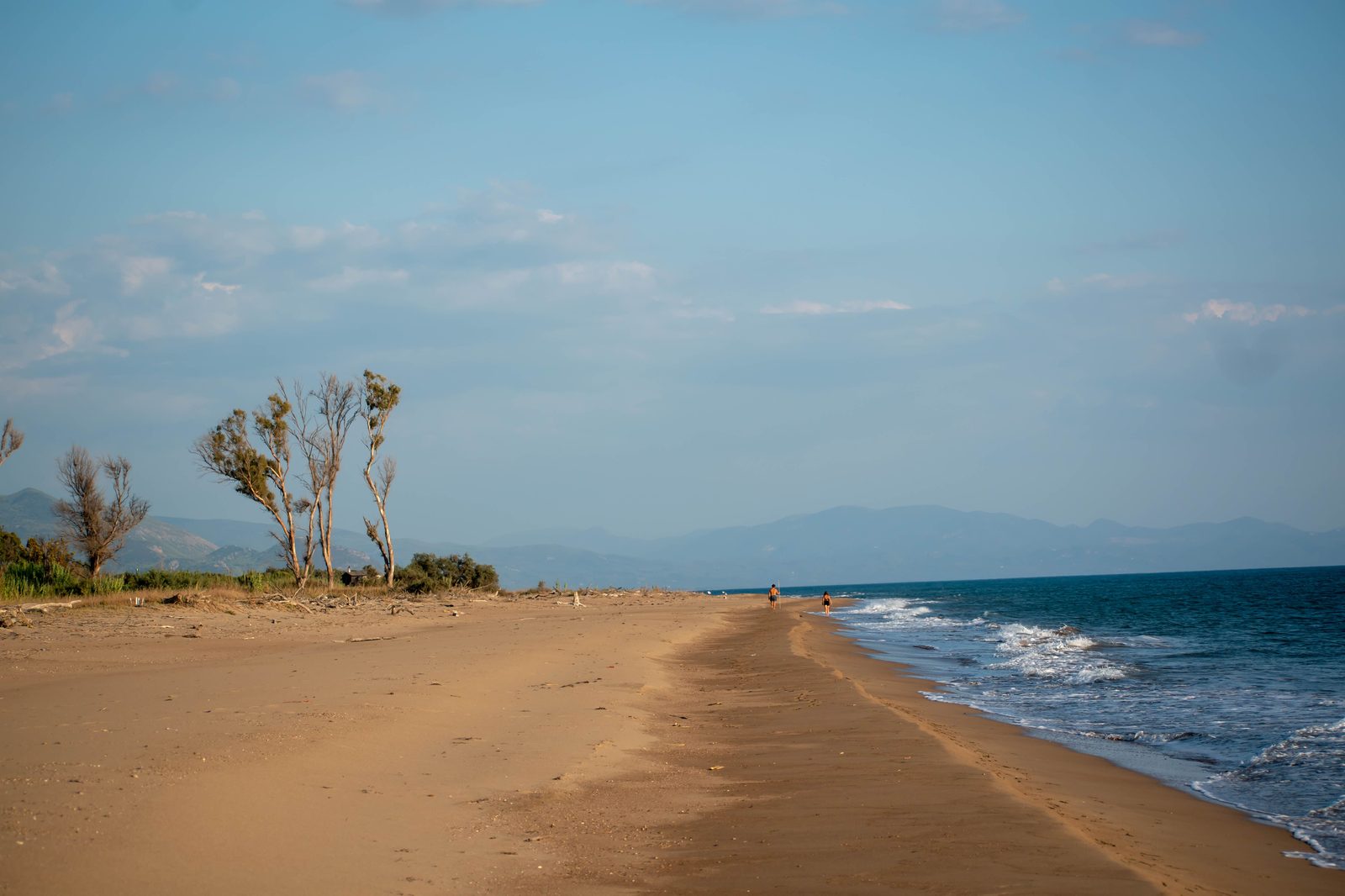 An empty tropical beach with calm water and a clear horizon