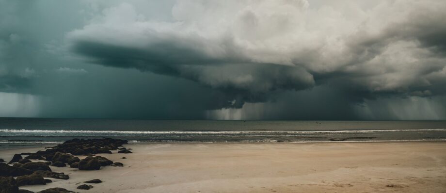 Dark storm clouds gathering over a calm tropical ocean under a heavy grey sky
