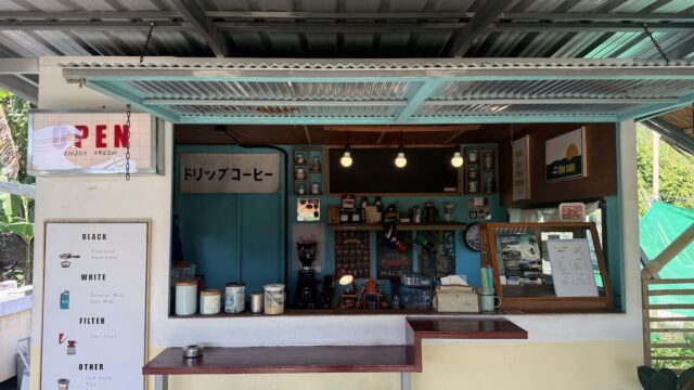 Small coffee shop with a blue counter, menu board, lights, jars, and decor. An OPEN sign hangs on the left side.